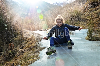 A girl slides on a frozen walking track (selective focus and some motion blur)