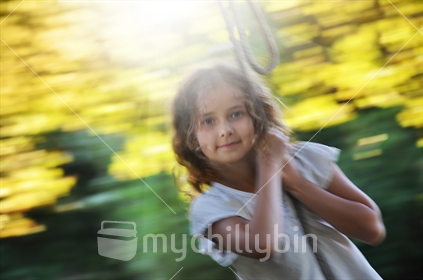Girl on a rope swing in Autumn - motion blur image
