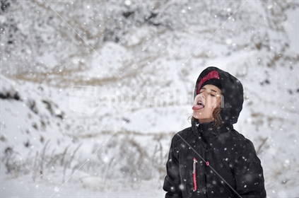 Girl with mouth open catching snowflakes