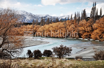 Winter view down the willow lined Shotover river toward the Coronet Peak ski field, Queenstown, South Island, New Zealand