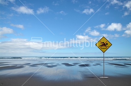 Danger. No swimming sign on black sand beach