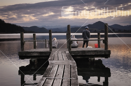 A family fishing off the jetty at dusk, Opoutere estuary, Coromandel, North Island, New Zealand