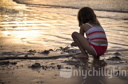 A young girl making sandcastles on the beach.