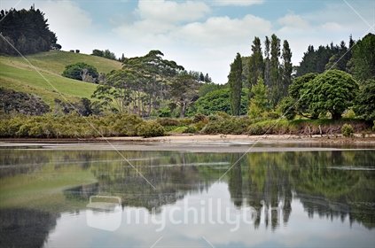 Scenic NZ coastal farmland, reflected in an estuary
