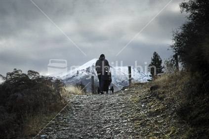 A man takes his baby for a walk at dusk in the hills near Queenstown. South Island, New Zealand