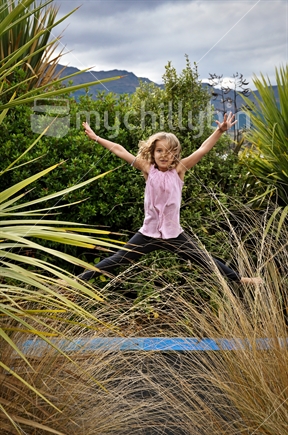 A happy young girl does a star jump on a trampoline (some motion blur)