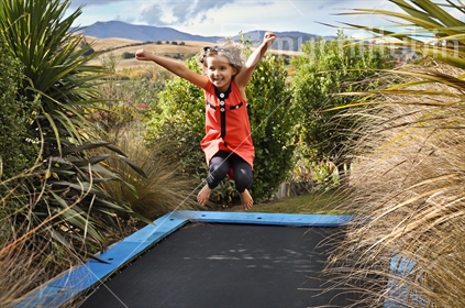 A happy young girl on a trampoline (some motion blur)