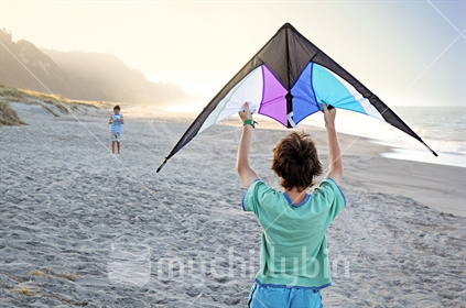 Teenage boys fly a kite on Matata beach near Whakatane, Bay of Plenty