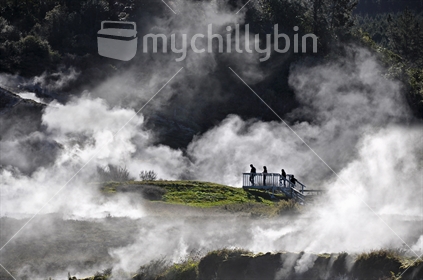Tourists amidst clouds of steam view geothermal attractions near Rotorua, North Island, New Zealand 