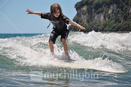 Young girl learning to surf (selective focus and some motion blur)