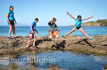 Kids jump into rock pools at Tawharanui regional park near Auckland (See also #100468_320 and #100468_415