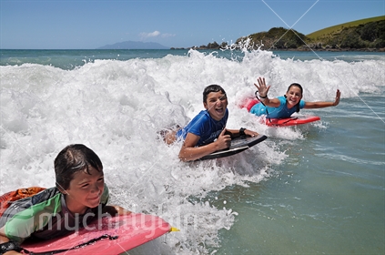 Kids catch a wave on boogie boards  (selective focus and some motion blur)