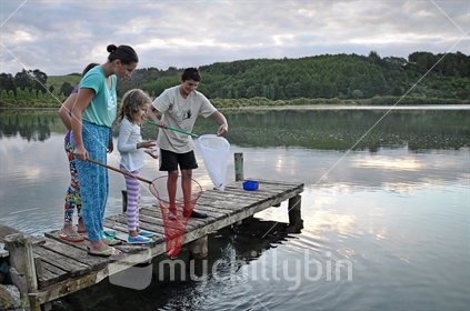 Kids bait fishing on a jetty at dusk (selective focus)