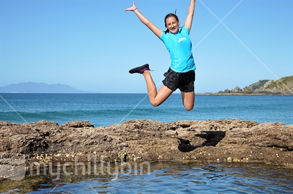 Girl jumps into rock pools at Tawharanui regional park near Auckland (See also #100468_557)