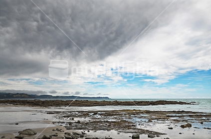 Rain clouds approach on a sunny day near Omaha beach, Rodney District near Auckland