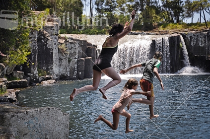 Family jumping at Charlie's Rock waterfall near Kerikeri, Northland (selective focus and some motion blur) See also #100468_415, #100468_557, #100468_571 and #100468_575
