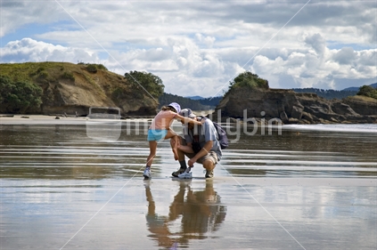 A father helps his daughter at Anchor Bay beach, Tawharanui Regional Park