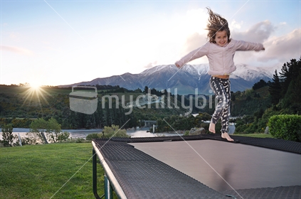 Girl on a trampoline with Mount Hutt in the background (Selective focus and motion blur)