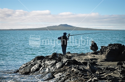 Fishermen in silhouette with Rangitoto in the background