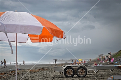 Orange umbrella, on Muriwai black sand beach (selective focus)