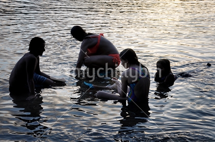 Kids relax in calm water at sunset