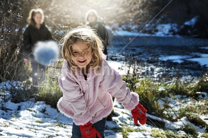 Young girl throws a snowball at Arrowtown River (motion blur)