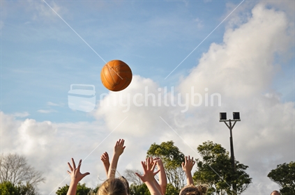 Girls compete for a netball (focus on ball)