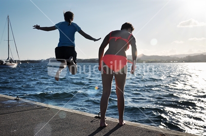 2 girls jump off a jetty (selective focus and motion blur)