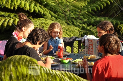Kids eat dinner amongst the tree ferns (see also Image #100468_757, and #100468_813)