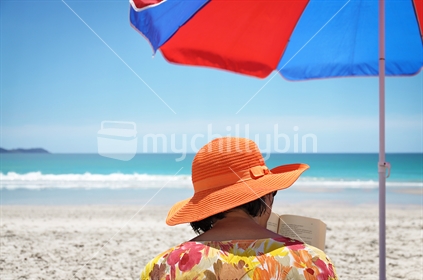Under a sun umbrella reading at the beach