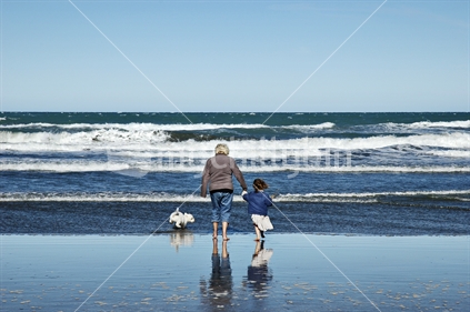 Grandmother and Granddaughter walk the dog at the beach