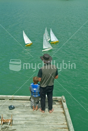 Man and boy sailing model yachts