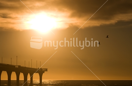 Seagulls fly north to their roosting spots before the sun sets over New Brighton Beach in Christchurch, New Zealand