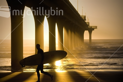 A longboarder charges along New Brighton Beach early in the morning as the sun begins to rise.
