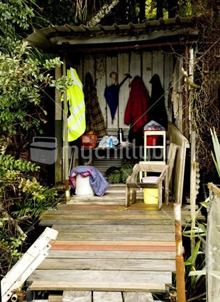 Whitebaiters hut in bush by river with old coats and chair