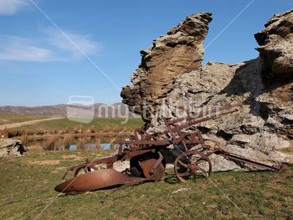 Vintage plough and rock formation near Omakau, Central Otago.