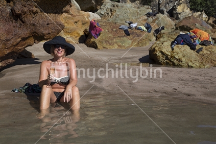 Lady enjoys a glass of champagne at Hot Water Beach