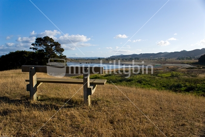 Wide view of a bench seat on a hill overlooking a bay