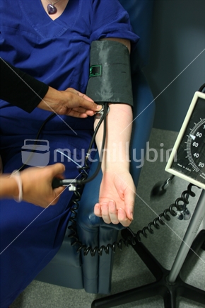 Doctor pumping up a blood pressure cuff on a patient