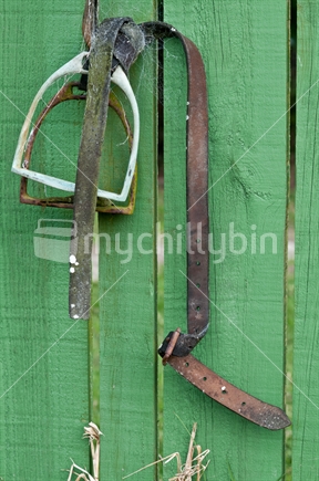 Stirrup irons, complete with cobweb, hanging on a fence.
