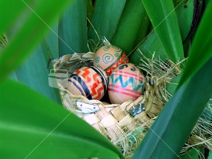 Home decorated easter eggs in harakeke basket in flax bush
