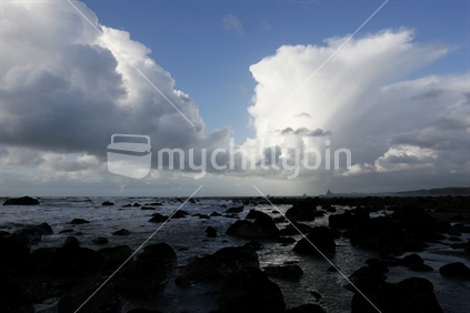 Tall clouds over rock pools, looking to New Plymouth, New Zealand