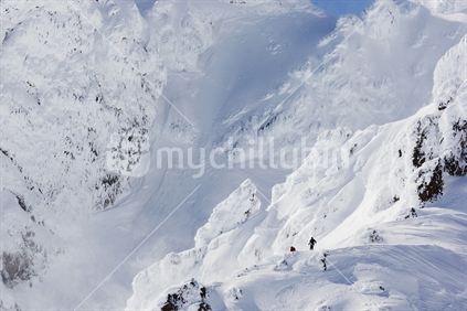 Group of skiers traversing under snow covered peaks near the top of Whakapapa ski field. North Island, New Zealand