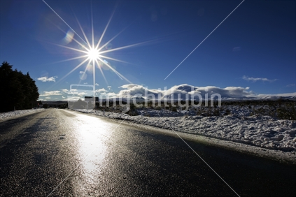 Sun shining on icy road looking towards Mt Tongariro and Ngauruhoe. North Island, New Zealand