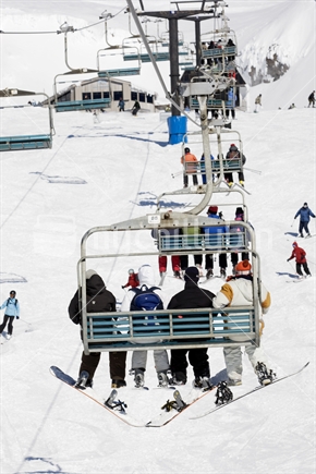 Snowboarders and Skiers on a chairlift at Whakapapa ski field. Mt Ruapehu, North Island, New Zealand