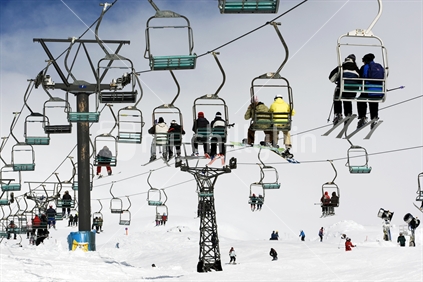 Snowboarders and Skiers on a chairlift at Whakapapa skifield. Mt Ruapehu, North Island, New Zealand
