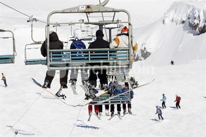 Snowboarders and Skiers on a chairlift at Whakapapa skifield. Mt Ruapehu, North Island, New Zealand