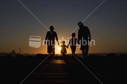 A family walking in front of a setting sun, New Zealand