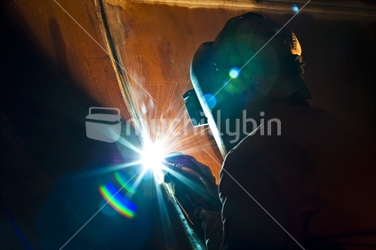 A welder working on a large project in a engineering workshop, New Zealand