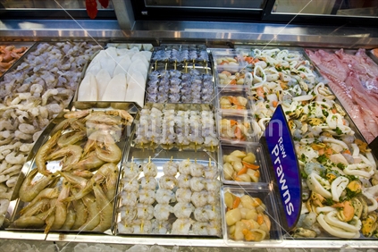 Fish and seafood on display in a refrigerated cabinet.